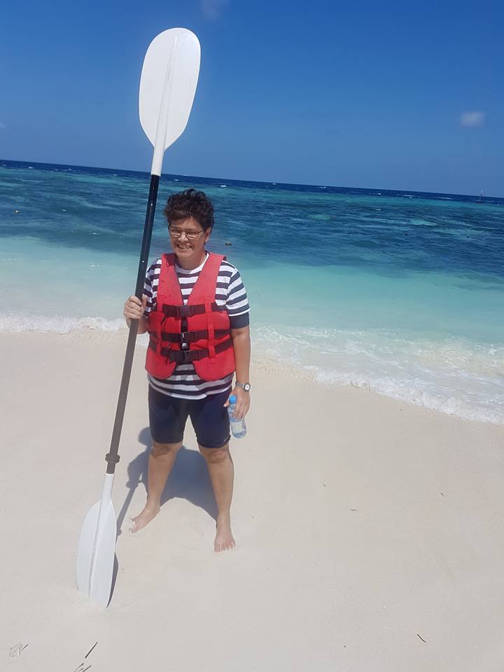 A woman with a paddle with the sea in the background