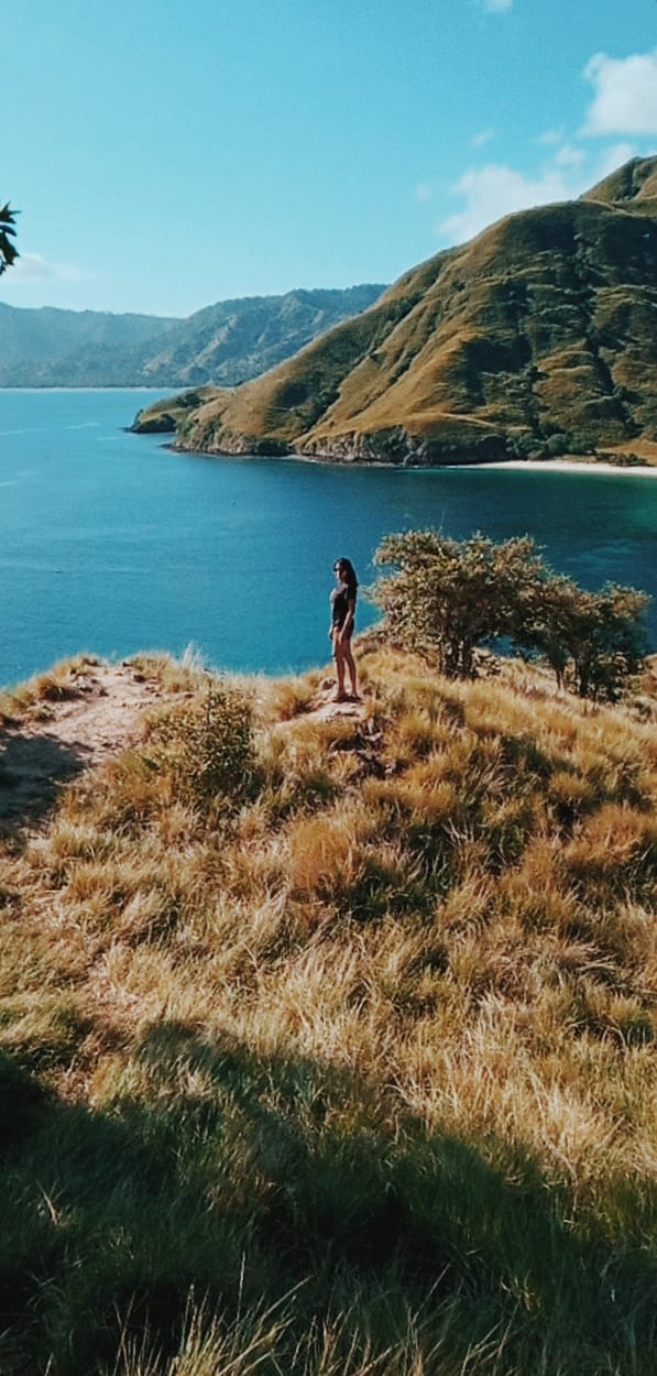 girl standing on cliff overlooking the sea